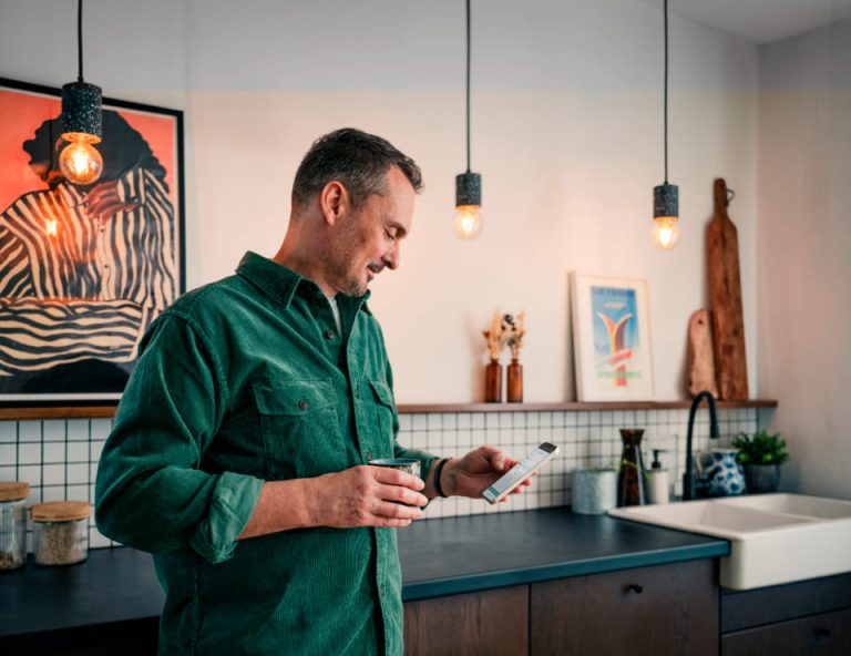 homme dans une cuisine qui consulte l'appli Mon Change