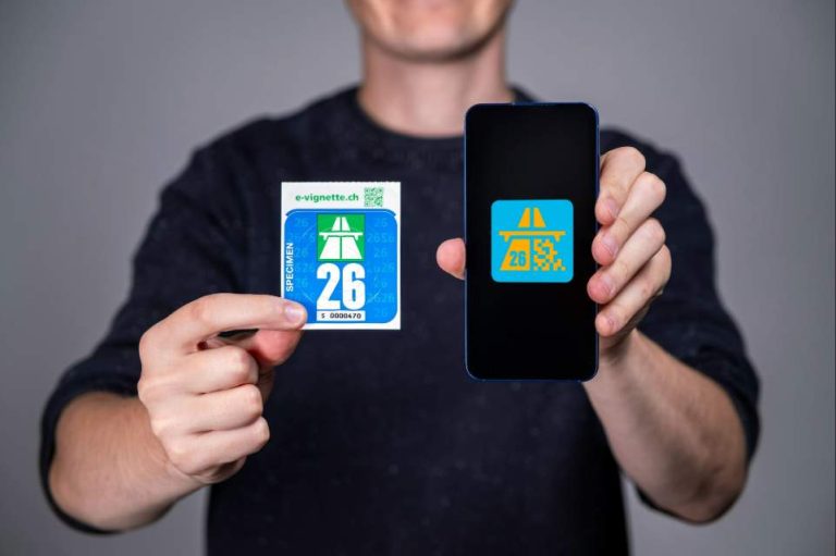 Personne tenant des ses mains la vignette suisse 2026 au format e-vignette et papier