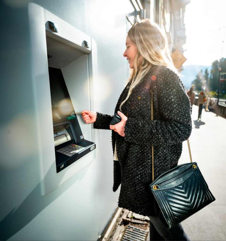 femme retirant de l'argent à distributeur de billet d'une banque