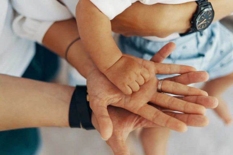 mains de parents qui tiennent la main de leur bébé